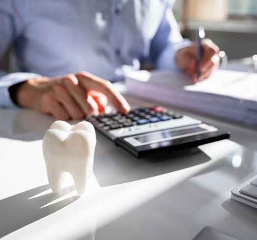 Person typing on a calculator while filling out paperwork